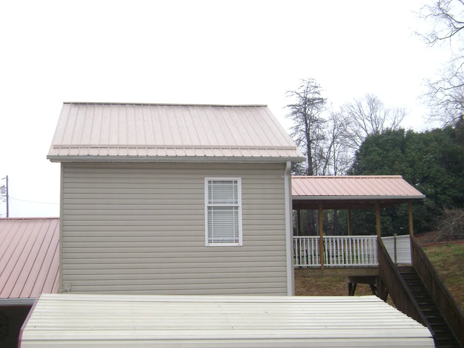 Tan metal roofs on a two story addition and attached porch, from a Roof Replacement job in Cape Coral