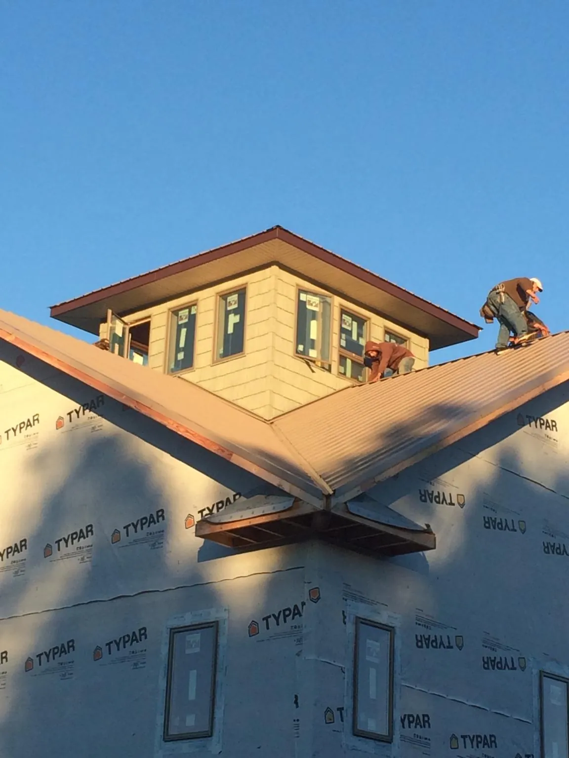 Roofers working around a rooftop cupola on a new metal roof at sunset — Roof Waterproofing in Cape Coral by Roofing Brothers